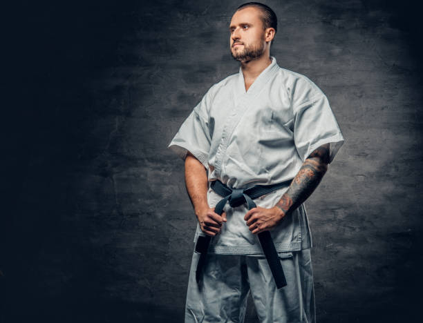 istock Karate fighter dressed in a white kimono over grey background. 940030722