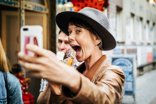 turista toma selfie mientras easting un helado - accesorio de cabeza fotos fotografías e imágenes de stock
