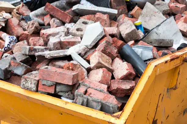 Photo of Yellow metal skip full of old bricks