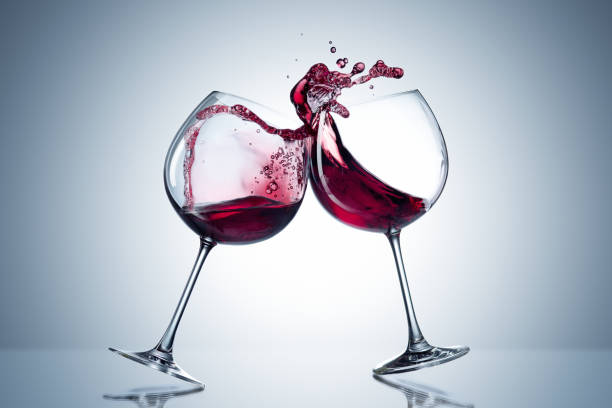 Two wine glasses in toasting gesture with big splashing. Alcohol concept. Two glasses of wine on the gray background Two wine glasses in toasting gesture with big splashing. Alcohol concept. Two glasses of wine on the gray background. Two transparent glasses. Trendy color. Merging alcohol wine glass knocked over stock pictures, royalty-free photos & images
