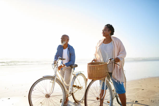 tout cet air frais apporte beaucoup de calme - senior couple cycling beach bicycle photos et images de collection