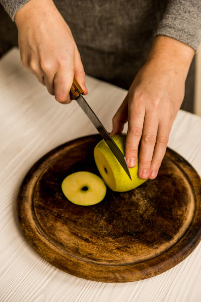 istock Woman cuts green apple on board close 940103860
