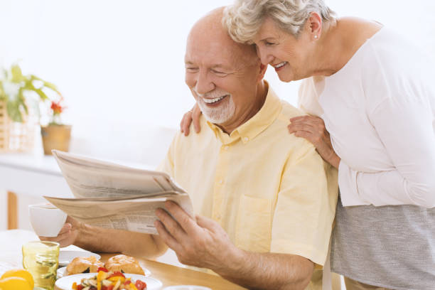 istock Senior reading newspaper with wife 940105218