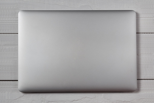 White closed laptop on wooden table background. Stiduo shot.