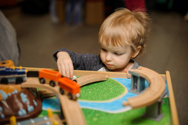 istock Cute little boy is playing with a toy wooden train 940118932