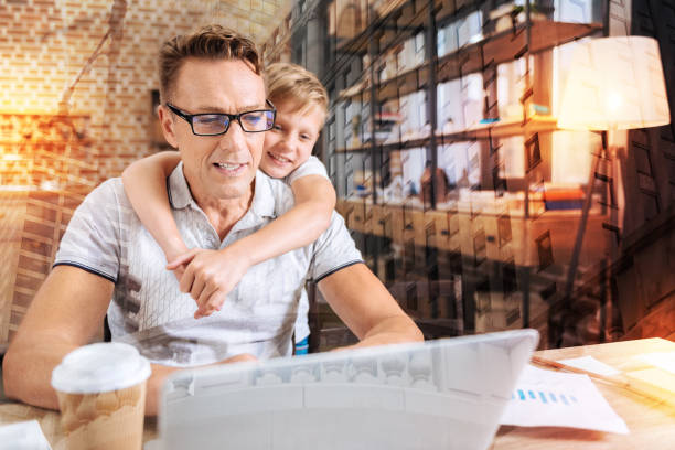 istock Attentive man looking at the screen while his son standing behind him 940122794