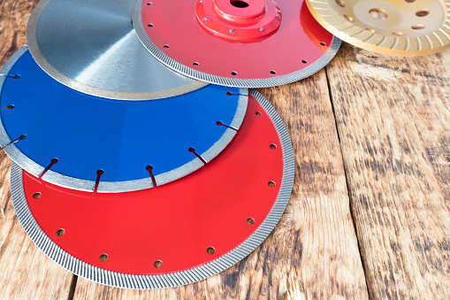 Red diamond wheels for granite and stone, blue for concrete, reinforced concrete, yellow for grinding concrete and stone, silver for cutting ceramic tiles on a wooden old board background