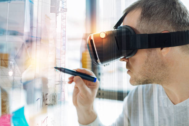 istock Serious man in virtual reality glasses looking calm and holding a marker 940137940