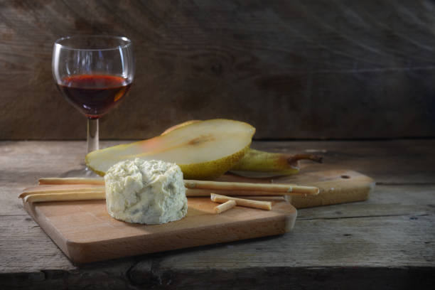 queijo stilton azul cremoso, vinho do porto, pera e alguns mordiscar varas em uma placa de corte contra um fundo escuro de madeira rústica, copie o espaço - port wine wine pear glass - fotografias e filmes do acervo