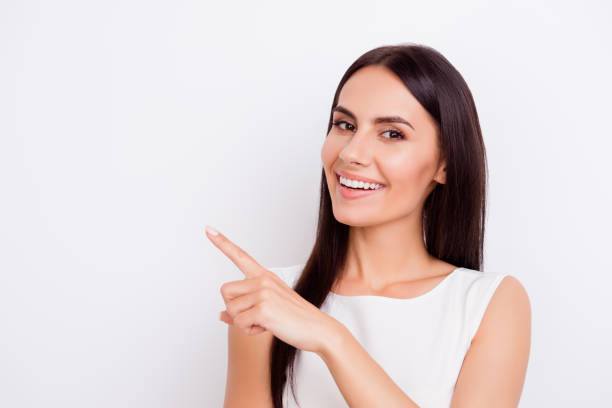 successful smiling businesslady is pointing away with finger. she is in isolated on the pure white background - beautiful one person happiness white imagens e fotografias de stock