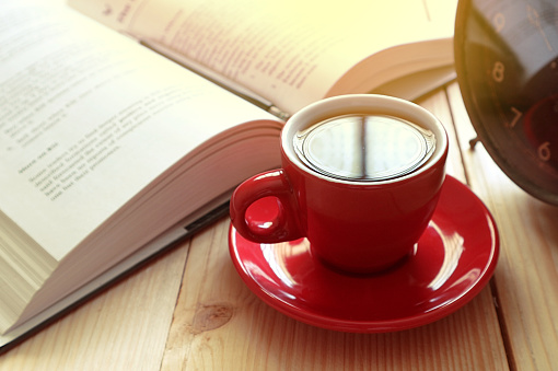Red coffee cup with background book and clock.