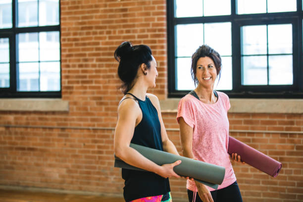 istock Yoga training class preparation. Two women having a discussion 940159632