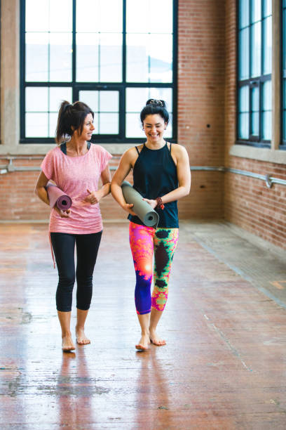 Yoga training class preparation. Two women having a conversation stock photo