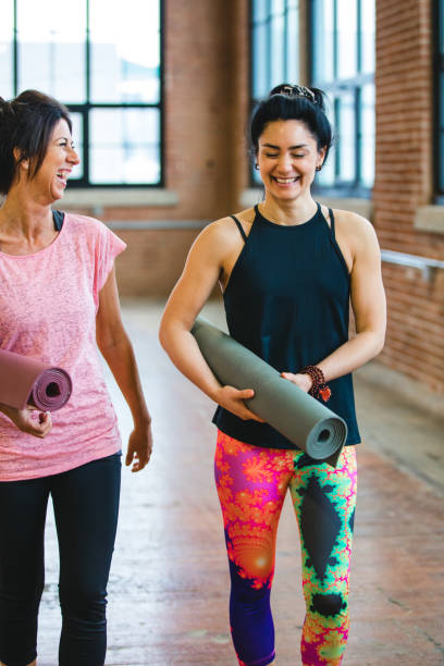 istock Getting ready for yoga. Two women laughing together 940159732