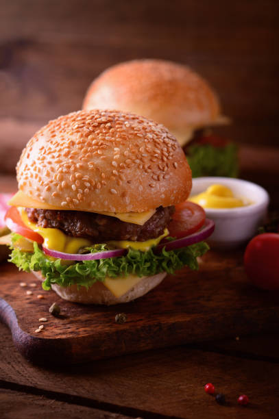 istock Fresh burger closeup. Wooden rustic background. Top view 940168020