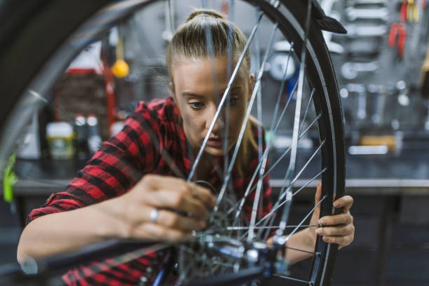 istock Stylish bicycle mechanic woman doing his professional work in workshop 940170862