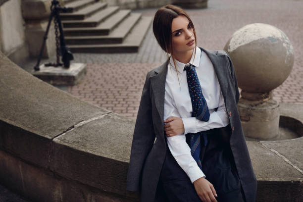 Beautiful Fashion Girl In Fashionable Clothing Posing In Street Fashion Girl In Fashionable Clothing In Spring. Beautiful Sexy Young Woman Wearing Stylish Womanly Fall Clothes Outdoors. Female Model In Elegant Overcoat, Shirt, Skirt, Tie Posing In Street In Autumn woman necktie stock pictures, royalty-free photos & images