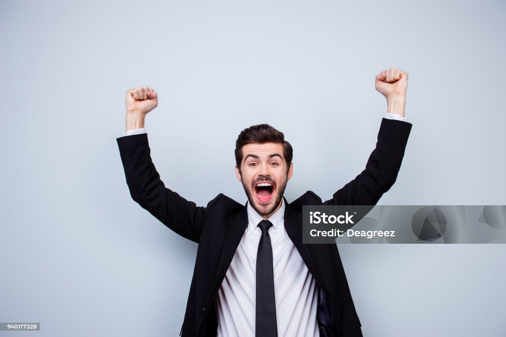 Happy excited man triumphing with raised fists on gray background Businessman Stock Photo