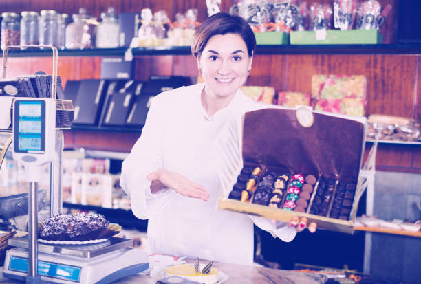 istock Shop assistant demonstrating box of chocolates 940178560