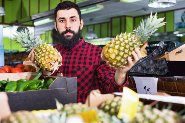 istock Young male seller offering pineapples 940178670