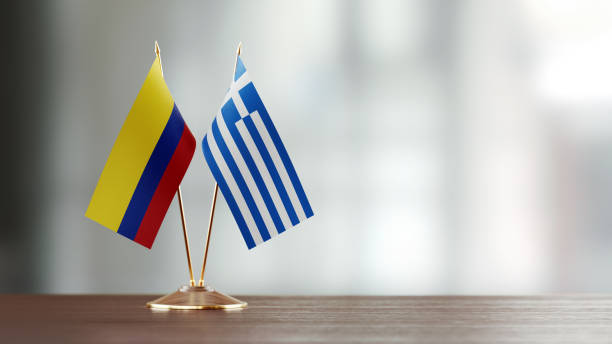 istock Colombian And Greek Flag Pair On A Desk Over Defocused Background 940189832