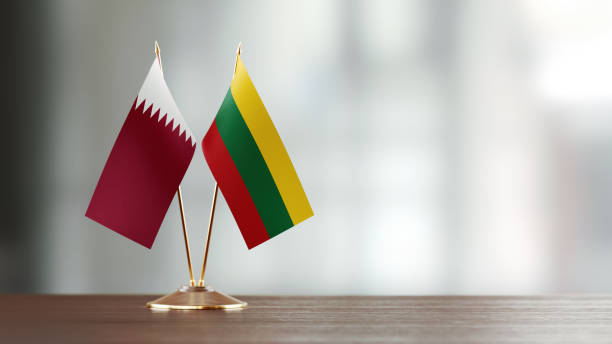 istock Qatari And Lithuanian Flag Pair On A Desk Over Defocused Background 940192780