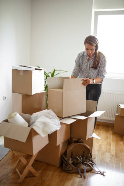istock Woman unpacking boxes in new home 940193058
