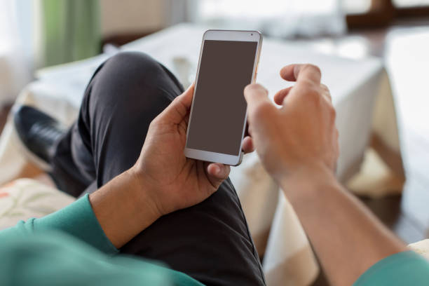 istock Male Using Smart Phone  with Both Hands, with Cosy Home Background 940193792