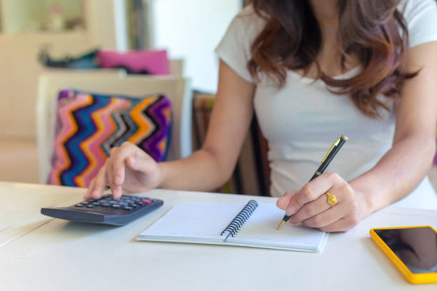 istock woman using calculator and make note calculate about cost at home. 940198268