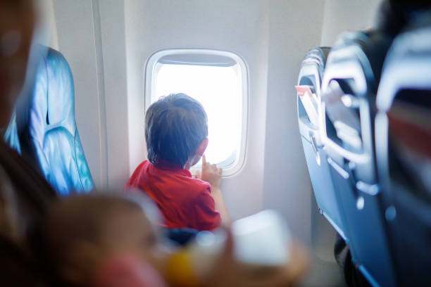 istock Little kid boy looking outside of plane window during flight on airplane. 940204270