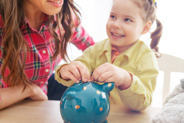 istock young mother teaches her daughter to save money. 940204484