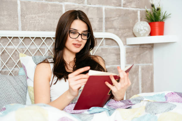 istock Girl reading a book in bed, smiling, happy and relaxed 940204670