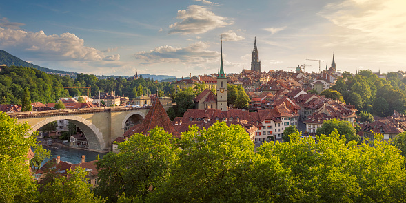 View of the city of Bern on a summer evening. On the left is the Nydeggbrücke (bridge), and the towers belong to the Nydeggkirche (church) and Berner Münster (Cathedral of Bern).