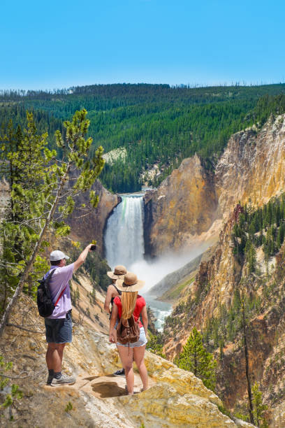 family taking photos of beautiful waterfall with phone. - yellowstone national park wyoming american culture landscape imagens e fotografias de stock