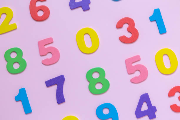 istock Multicolored wooden numbers texture on pastel rose background minimalistic concept. 940255454