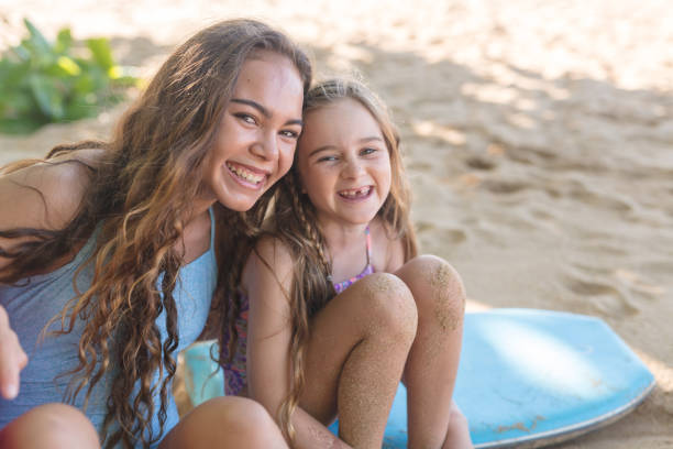 istock Two sisters relax with their boogie boards at the beach 940259636