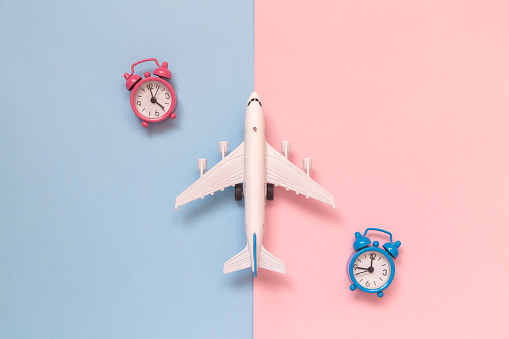 Airplane model with two small alarm clocks flat lay. Travel minimal creative concept.
