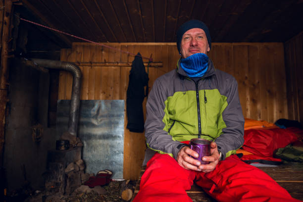 smiling adventurer is drinking coffee and dreaming - home interior cabin shack european alps imagens e fotografias de stock