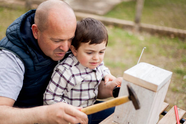 istock Father and son building birdhouse outdoor 940263924
