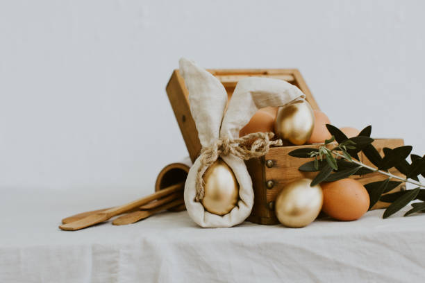 istock Rustic Happy Easter. Funny eggs with linen napkin on Rural background 940264566