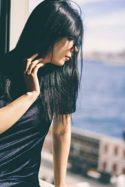 istock beautiful women near window looking sea 940267670