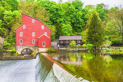 Clinton, New Jersey, USA-April 25, 2010- Soft green colors of early spring contrast with the bright red of the old mill in Clinton New Jersey reflected in the Raritan River.