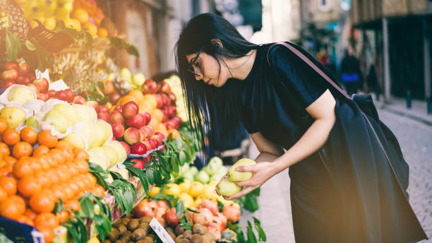 femme, acheter des fruits sur le marché de la rue - fruits et légumes photos et images de collection