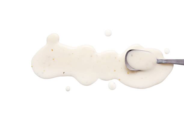 splashes and spilled ranch dressing with a spoon. isolated on white background. flat lay, top view spilling stock pictures, royalty-free photos & images