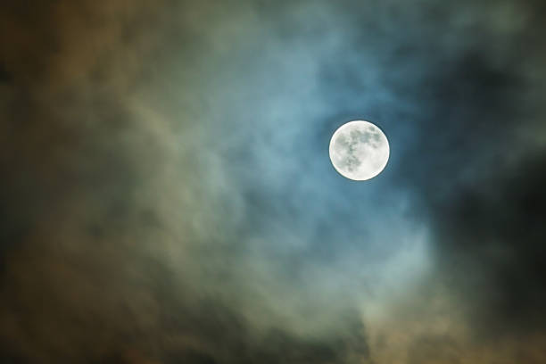 istock Mysterious view of full moon disk in the night sky through the clouds 940287994