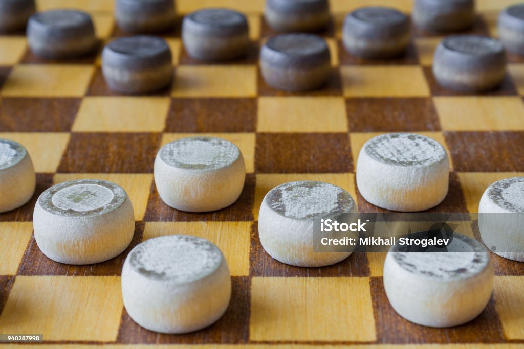 Fragment of wooden checkerboard with checkers spaced on table (closeup) Agricultural Field Stock Photo