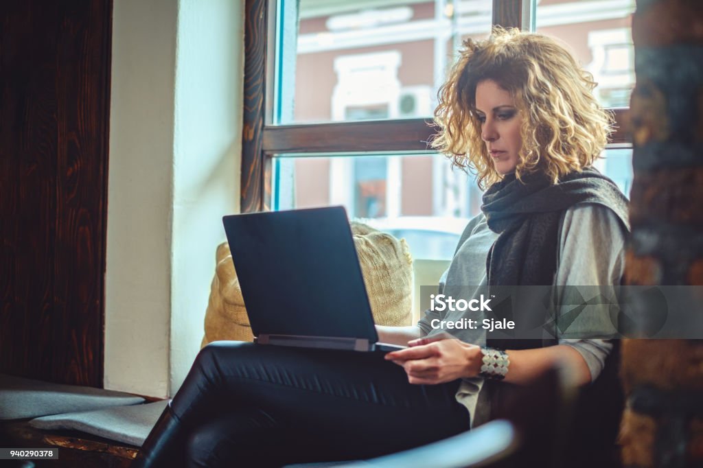Woman with curly hair working seriously on her laptop Woman with curly hair working seriously on her laptop in a cafe Adult Stock Photo