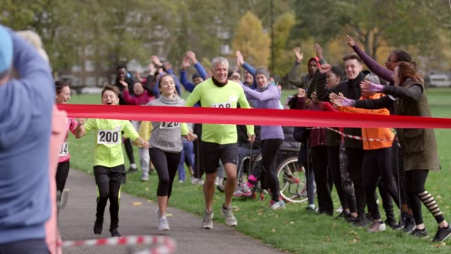 Spectators cheering for family runners crossing finish line at charity fun run