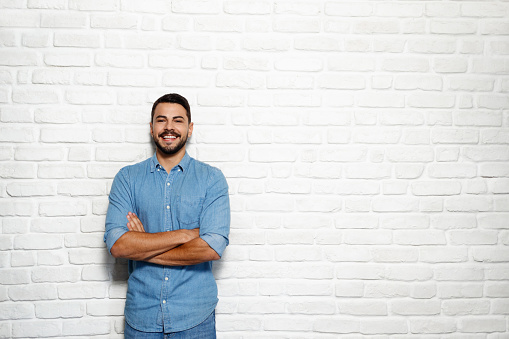 Portrait of happy Italian man smiling against white wall as background and looking at camera.