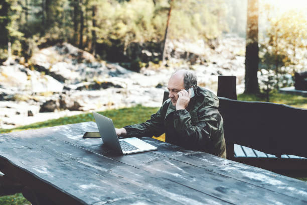 istock Man entrepreneur with laptop talking on the phone in forest 940303054